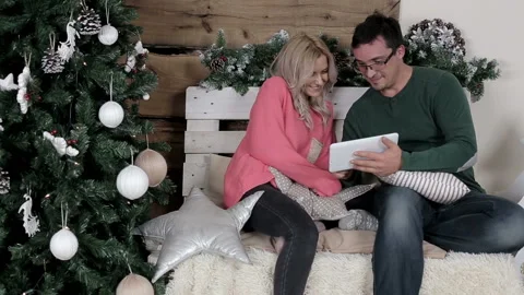 Young couple sitting on the chair and browsing the internet on the tablet Stock Footage