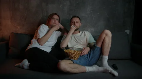 A young couple is sitting on the couch and watching a movie on TV Stock Footage 197777482
