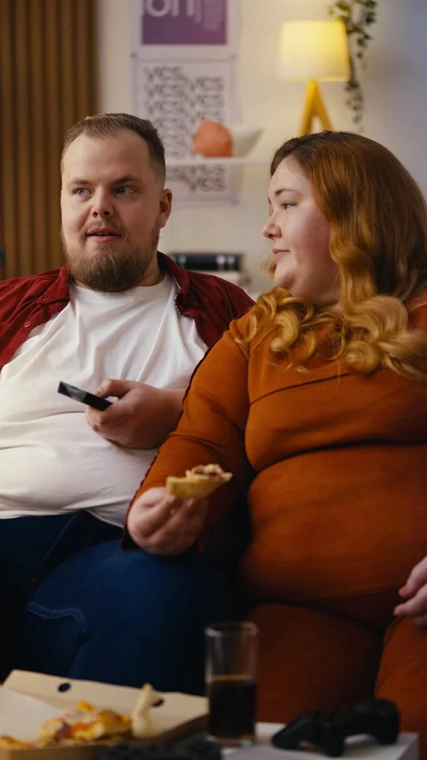 Young couple sitting on the couch, eating pizza and flipping through channels Stock Footage 306373383
