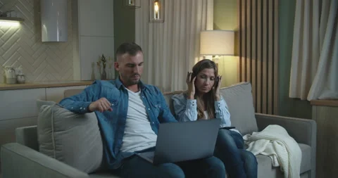 A young couple is sitting on the couch. A man works on a laptop and a girl Stock Footage 149920158