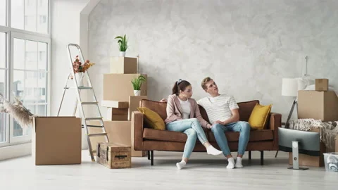 Young Couple Sitting on Couch in New Home Discussing Home Plan. Couple Stock Footage 146705184