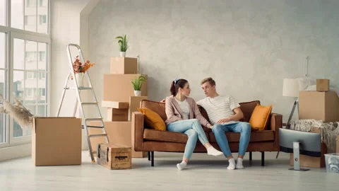 Young Couple Sitting on Couch in New Home Girl POinting to Side. Couple Stock Footage 217507591