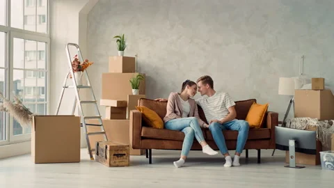 Young Couple Sitting on Couch in New Home Discussing Home Plan. Couple Stock Footage 217671867