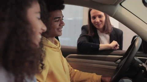 Young couple is sitting inside car and talking to consultant at dealership Stock-Footage 183001985