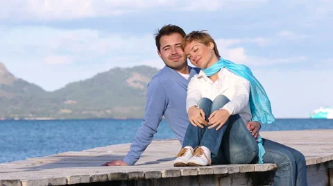 Young couple sitting on the jetty Stock Footage 57764029