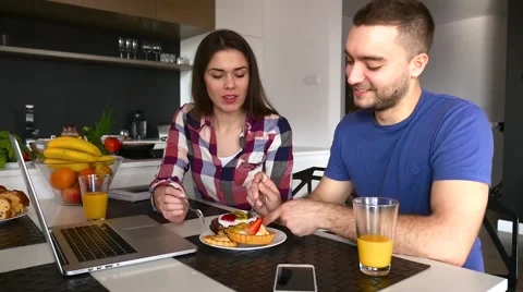 Young couple sitting in the kitchen and tasting capcakes with fruits Stock Footage 61857900