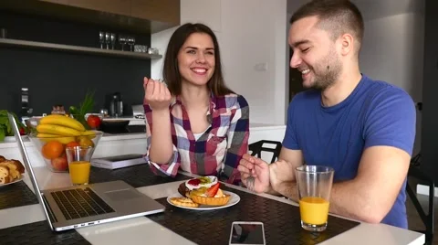 Young couple sitting in the kitchen and tasting capcakes with fruits. Stock Footage 61858223