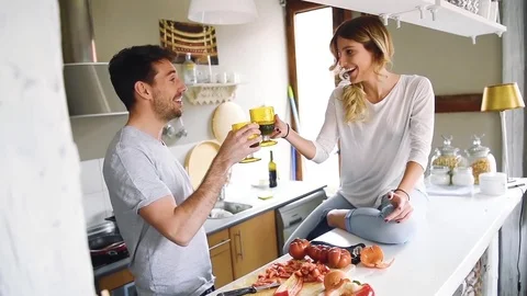 Young couple sitting at kitchen and clinking wineglasses Stock Footage 74728494