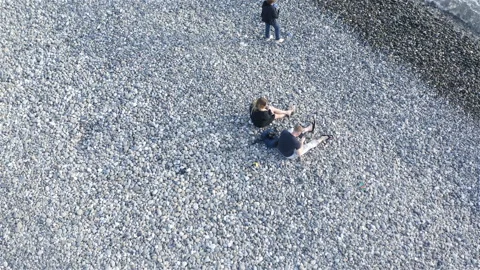 A young couple is sitting on a large pebble by the sea Stock Footage 134704175