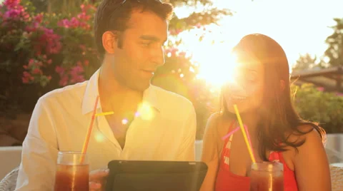 A young couple sitting outside using a tablet during magic hour Видео 33847583