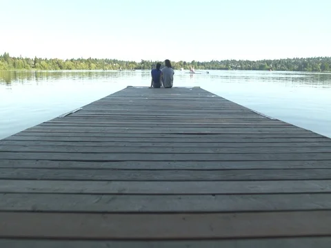 A young couple sitting on a pier 動画素材 76223899