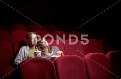 Young couple sitting at red movie theatre Stock Photos