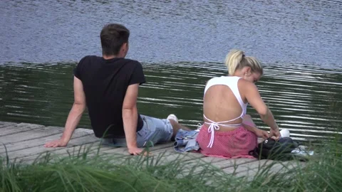 Young couple sitting by the river, and a girl with a dog go around Video stock 159074356