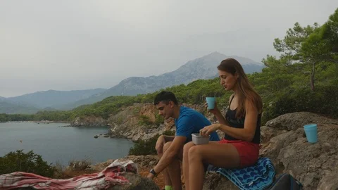 Young couple sitting on rocks in forest eating picnic Stock Footage 104090247