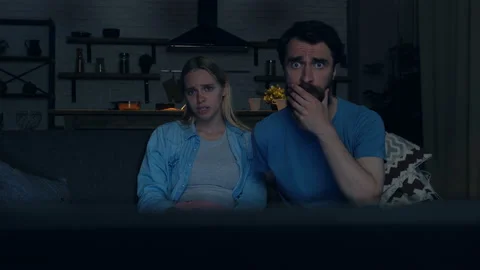 Young couple sitting on the sofa and watching horror movie. Stock Footage 108862759