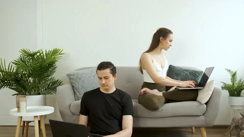 Young couple sitting on sofa and floor meditating and working on laptop. Work at Stock Footage 140619003
