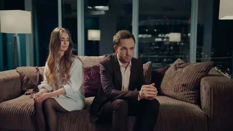 Young couple sitting on sofa on a date at home and looking upset at each other. Stock Footage 219826188