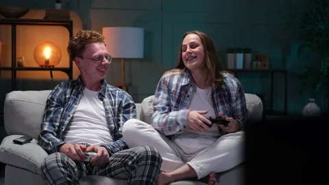 Young couple sitting on sofa playing video games Stock Footage 166098459