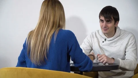 Young couple sitting at a table in a cafe and talk Stock Footage 71497302