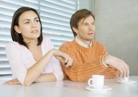 Young couple sitting at table with cups of coffee Stock Photos