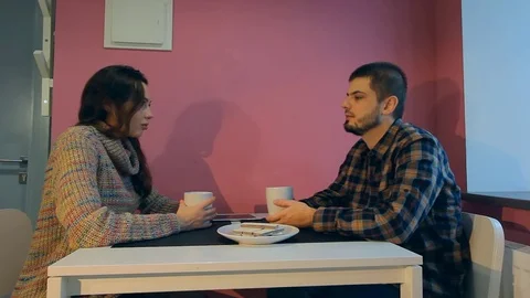 Young couple sitting at the table in their apartment, drinking a morning coffee Stock Footage 70588704