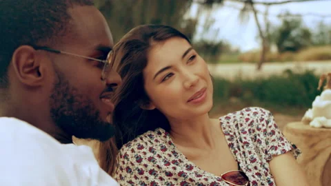 Young couple sitting, talking, laughing and enjoying their company on the beach Stock Footage 199459784
