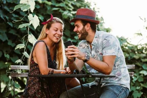 Young couple sitting on the terrace using smartphone Stock Photos