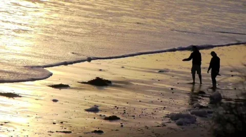 Young Couple Skipping Stones on Beach at Sunset Stock Footage
