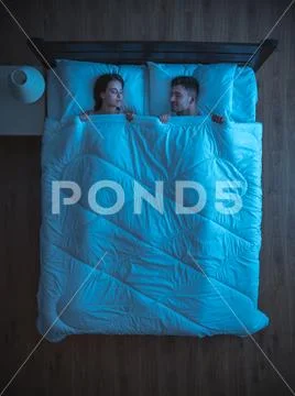 The young couple sleeping on the bed. night time. view from above Stock Photos