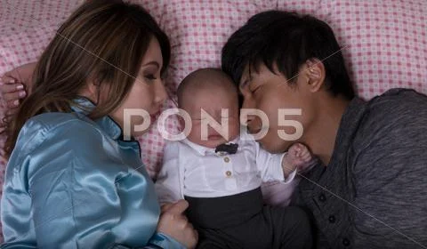 Young couple sleeping with infant baby in bed Stock Photos