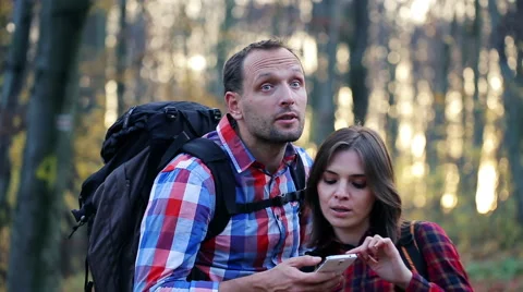 Young couple with smartphone looking for direction in autumn forest HD Stock Footage 43770324