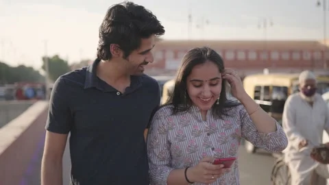 A young couple is smiling and using mobile phone next to busy city street Stock Footage 151959077