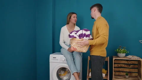 Young couple smiling confident holding basket with clothes at laundry room Stock Footage
