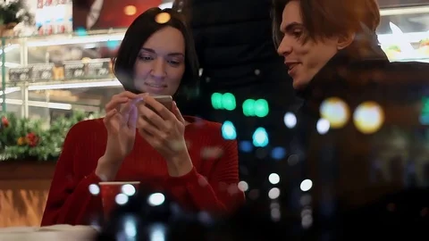 Young couple smiling talking about something sitting in cafe in evening Stock Footage 83082477