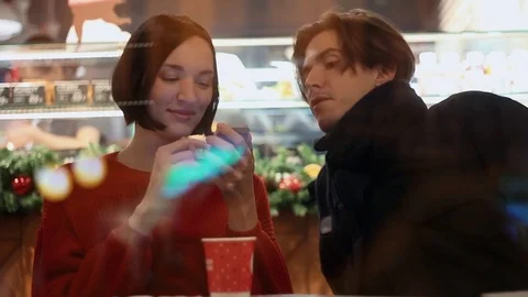 Young couple smiling using smartphone sitting in cafe. Christmas time Stock Footage 83082413