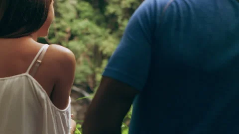 Young couple smiling while backs to camera in front of small waterfall in an Aus Video stock 199459952