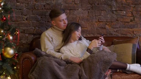 Young couple on a sofa under a cozy blanket on the background. Video stock 119513253