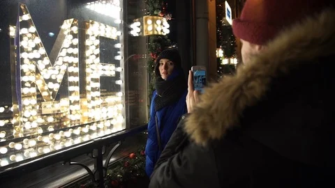 Young couple spend time together on busy city street in evening taking photo Stock Footage 83874589