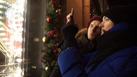 Young couple spends time together on busy urban street in evening taking photo Stock Footage 83918160
