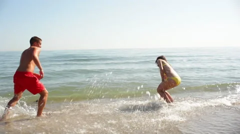 Young couple splashing on beach Stock Footage 43618142