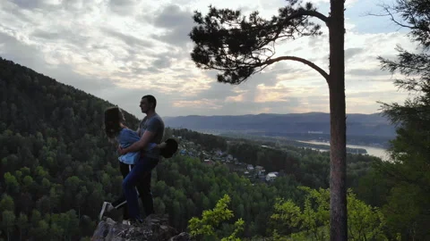 A young couple stand on the edge of a cliff and kiss. Stock Footage 111122116
