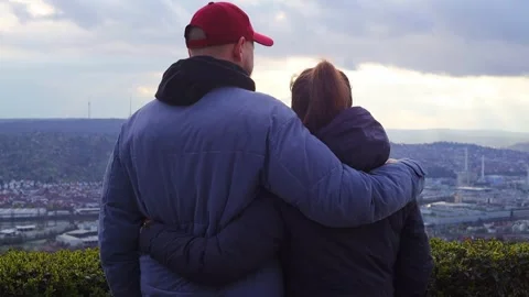A young couple stand embracing looking at the panorama of the city Stock Footage 251475725