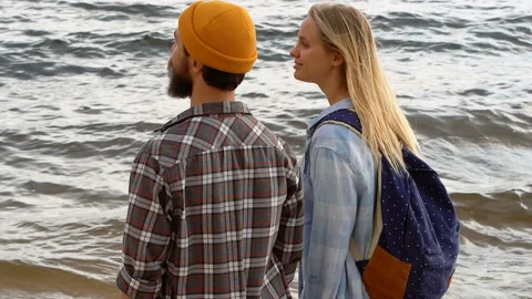Young couple standing on the beach, looking at the sea, enjoying life. Video stock 109340328