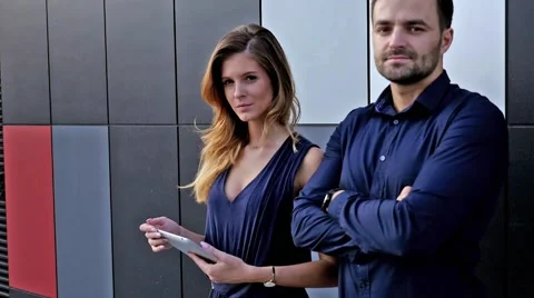 Young couple  standing in front of modern building. Woman is holding tablet pc. Stock Footage 55391156