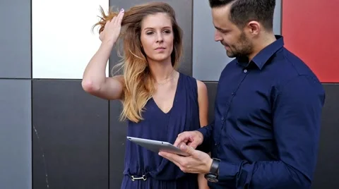 Young couple  standing in front of modern building. Man is holding tablet pc Stock Footage 55891483