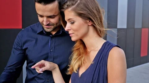 Young couple  standing in front of modern building. Man is holding tablet pc Stock Footage 55892356