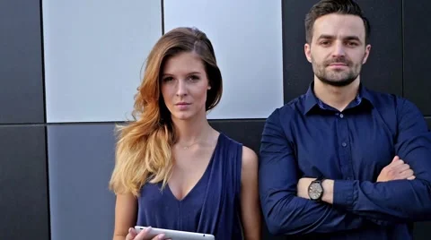 Young couple  standing in front of modern building. Woman is holding tablet pc Stock Footage 56304420