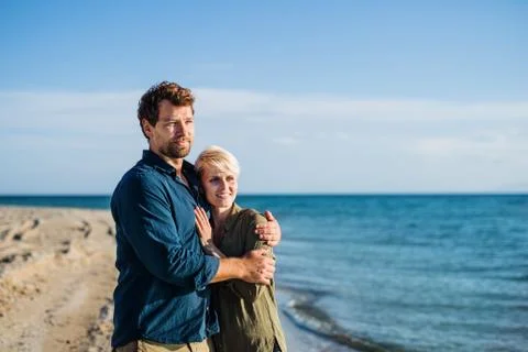 Young couple standing outdoors on beach, talking. Copy space. Stock Photos