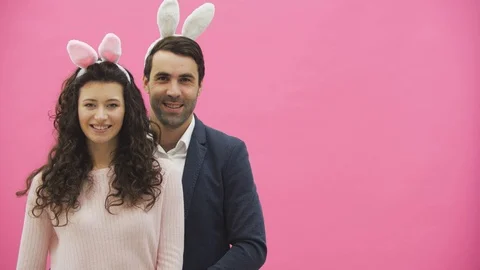Young couple standing on a pink background. During this, the gesture class shows Video stock 104808694