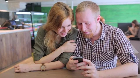 Young couple surfing the web looking at photos on mobile phone Stockbeeldmateriaal 74459441